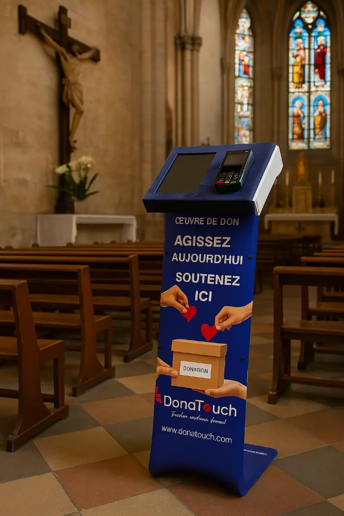 Borne DonaTouch pour lieux de culte, utilisée pour les offrandes et le soutien aux œuvres religieuses par paiement électronique sécurisé.  Exporter vers Sheets Borne de dons DonaTouch bleue et blanche dans une église, à côté d'une croix et de bancs en bois. L'écran affiche "Œuvre de don - Agissez aujourd'hui - Soutenez ici".